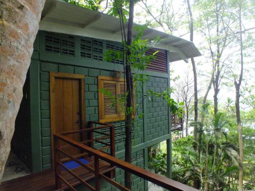 a green house with a wooden door and a porch at Casa Galú - Capurganá in Capurganá