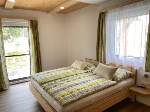 Bett in einem Zimmer mit einem großen Fenster in der Unterkunft Hofbauer-Hof in Rastenfeld