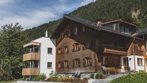 a large wooden house in the mountains at Tante Anna Apartments in Sankt Gallenkirch