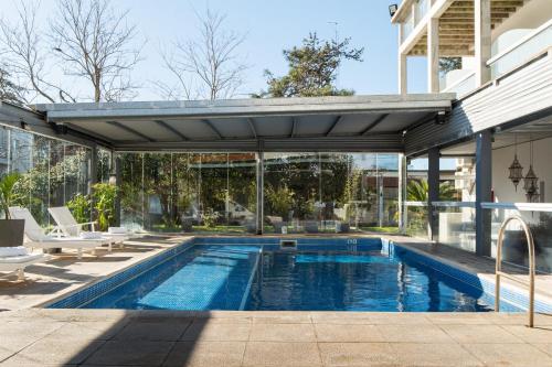 una piscina en una casa con un edificio en Hotel Valeria Apart & Hotel Spa en Valeria del Mar