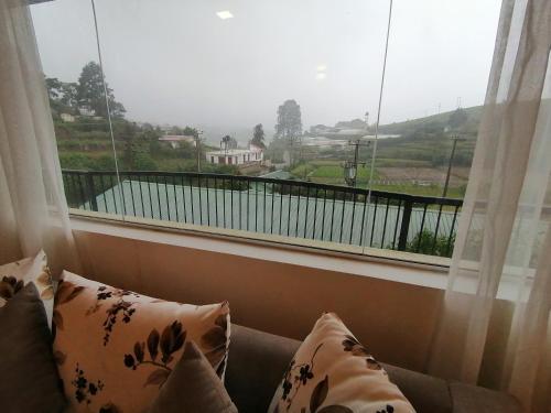 a room with a large window with a couch and a view at Moon Plains Luxury Apartments in Nuwara Eliya