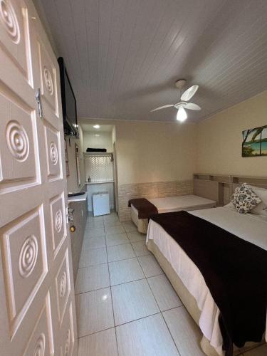a hotel room with two beds and a door at Pousada Recanto da Ana Alice in Abraão