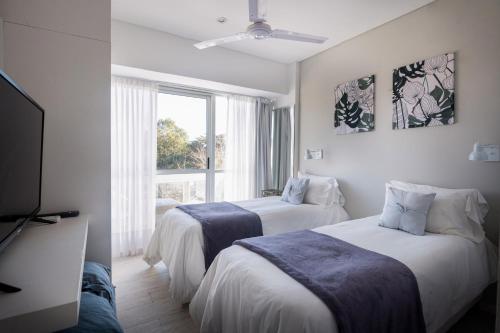 a bedroom with two beds and a tv and a window at Hotel Valeria Apart & Hotel Spa in Valeria del Mar