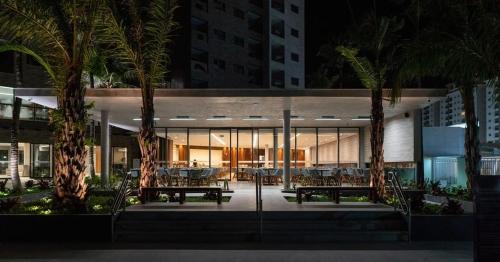 a building with two benches and palm trees at night at Salinas Premium Resort in Salinópolis