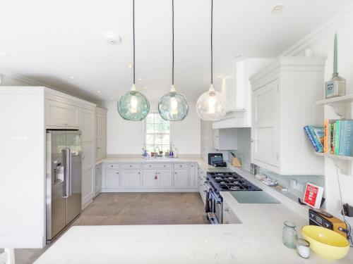 a white kitchen with white cabinets and silver appliances at The White House - Bordon in Bordon