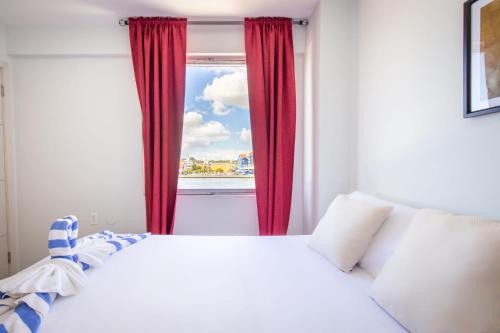 a bedroom with a bed and a window with red curtains at World Heritage Apartments in Willemstad