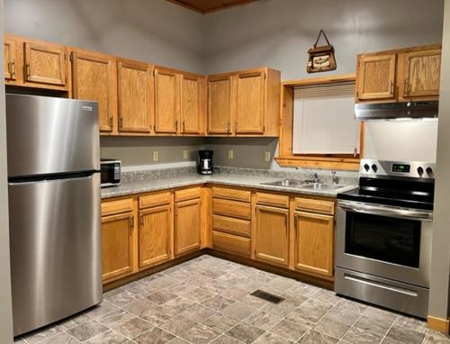 a kitchen with wooden cabinets and stainless steel appliances at Stay In Ohiopyle - closest place to the GAP trail in Ohiopyle, PA, Hot Tub in Ohiopyle