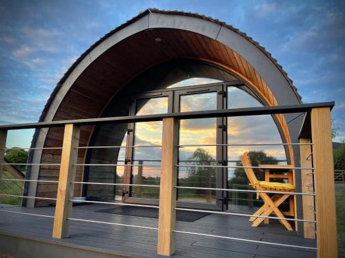 a circular house with a window and a chair on a deck at Hood Lane Farm - The Pod - Luxury Glamping Holiday Lodge in Arley