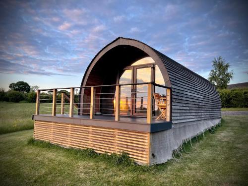 a small building with a large window in a field at Hood Lane Farm - The Pod - Luxury Glamping Holiday Lodge in Arley