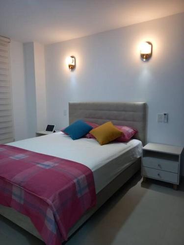 Un dormitorio con una cama con almohadas de colores. en Edif. Deymar - Departamento frente al mar 9no piso, en Tonsupa