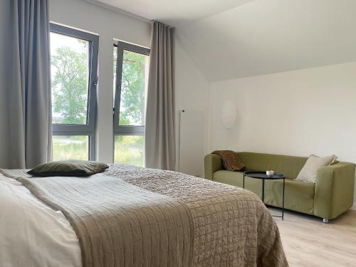 a bedroom with a bed and a couch and a window at Bieleniówka in Nakielno