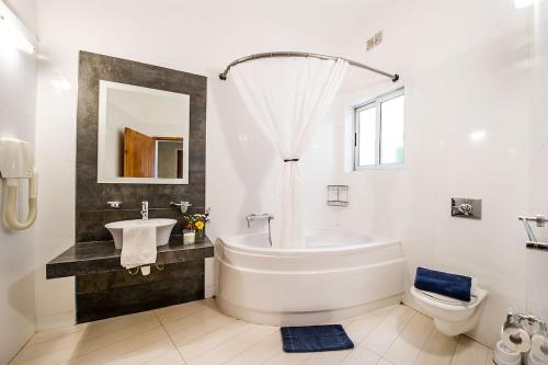 ein weißes Badezimmer mit einer Badewanne und einem Waschbecken in der Unterkunft The Arches Holiday Home in Kerċem