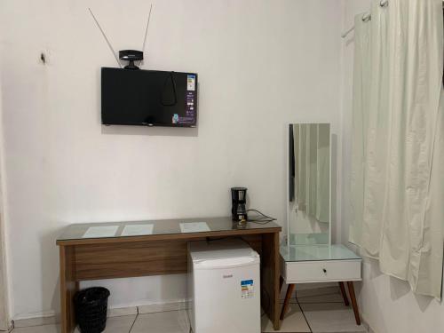 een kamer met een bureau en een televisie aan de muur bij Pousada Meu Xodó in Barreirinhas