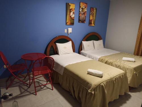 two beds in a room with a chair and a table at HOTEL ALFONSO UGARTE in Chiclayo