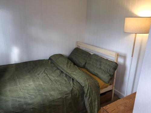 a small bedroom with a bed and a lamp at Mini cabin in a quiet area in London