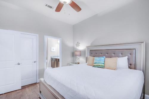a white bedroom with a large bed with a ceiling fan at Alerio B203 in Destin