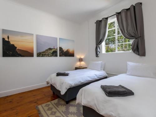 1 dormitorio con 2 camas y ventana en Jonkershoek Valley Cottage en Stellenbosch