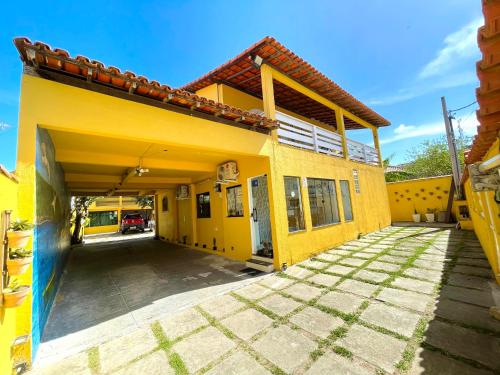 a yellow house with a driveway in front of it at Pousada Toca dos Coelhos in Arraial do Cabo