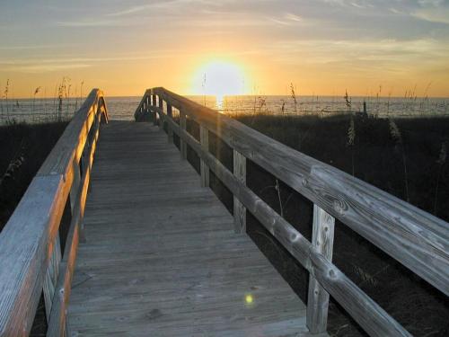 a wooden boardwalk leading to the beach at sunset at Land's End 11-203 Beach Front - Premier in St Pete Beach