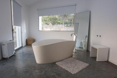 baño con bañera blanca y ventana en La Maga Rooms, en Xàtiva