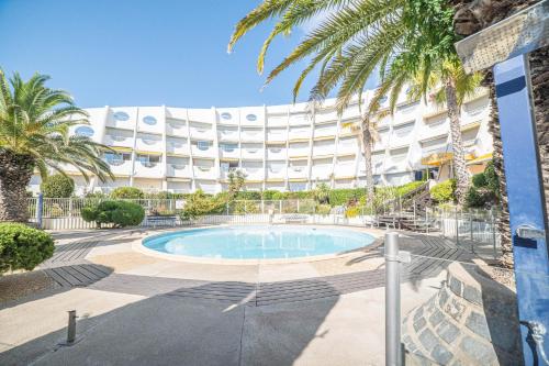 une piscine devant un immeuble avec des palmiers dans l'établissement VILLA SUNNY BEACH CLIM ACCES PLAGE PARKING FAMILLE - TopProsConciergerie, à La Grande Motte