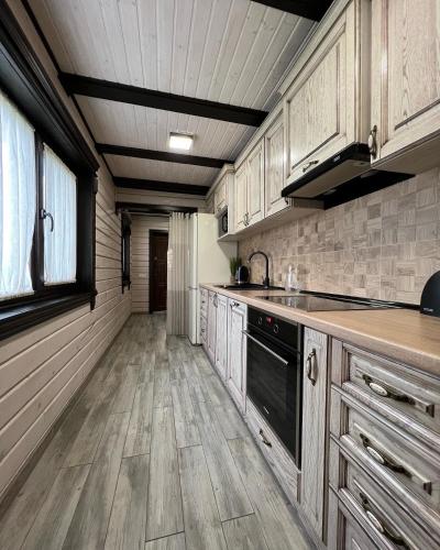 a kitchen with wooden cabinets and a large window at Villa Family House Truskavets in Modrychi