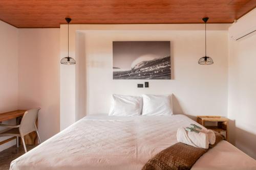 a bedroom with a white bed with a wooden ceiling at Esencia Nativa in El Zonte