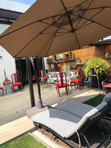 d'une terrasse avec un parasol, des chaises et des tables. dans l'établissement Habitaciones Coyoacan (UNAM), à Mexico