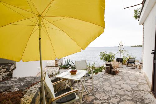 a yellow umbrella and a table and chairs with the ocean at Apartments Ziva in Primošten