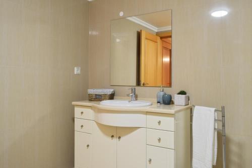 uma casa de banho com um lavatório e um espelho em Machico Beach, a Home in Madeira em Machico