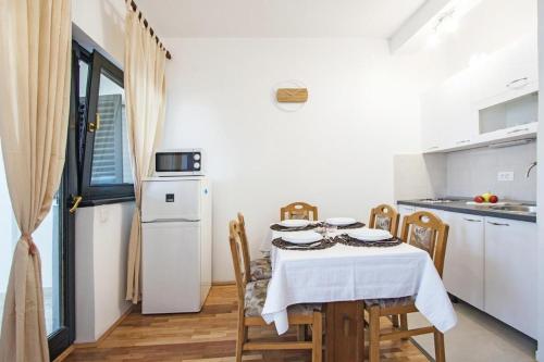 a kitchen with a table with chairs and a white refrigerator at Apartment Andrejka in Peroj