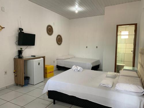 a room with two beds and a television in it at Pousada Meu Xodó in Barreirinhas