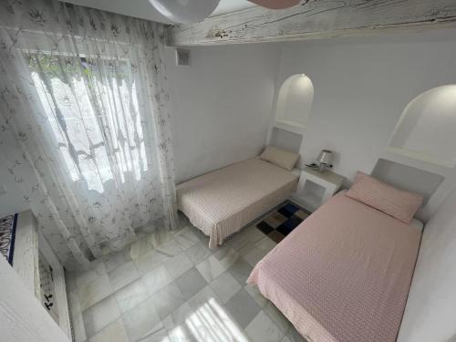 トレビエハにあるPerla del Marのベッド2台と窓が備わる小さな客室です。