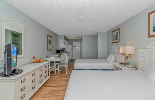 a bedroom with two beds and a desk with a television at Ocean View Double Queen Suite with Full Kitchen! Sea Mist Resort 50804 - Perfect for 2-4 guests! in Myrtle Beach