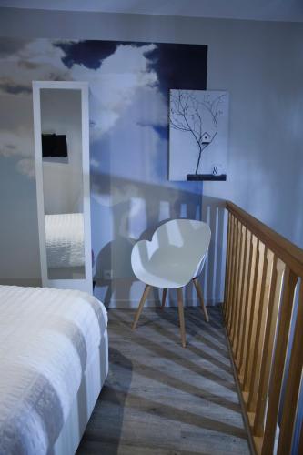 a bedroom with a white chair next to a bed at Studios Design by Les Béthunoises in Béthune