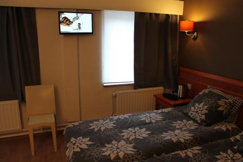 a bedroom with a bed and a tv on the wall at Hotel De Ploeg in Diepenbeek