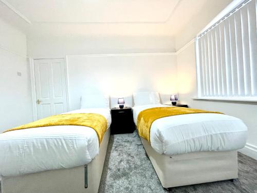 two beds in a bedroom with white walls at Lotus Home Wallasey in Wallasey