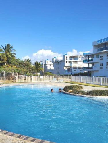 two people swimming in a large swimming pool at Beautiful beachside apartment w/ terrace, balcony. in Arenas