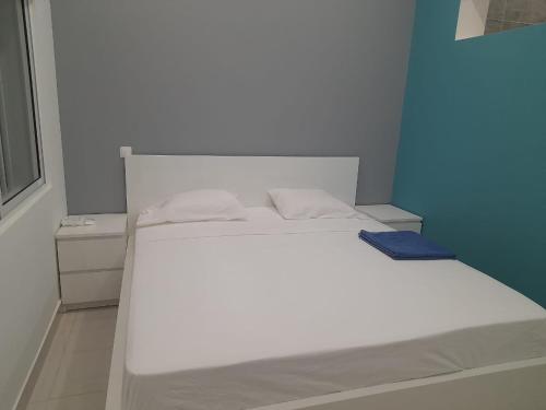 a white bed in a room with a blue wall at Apartamentos Morabeza in Mindelo
