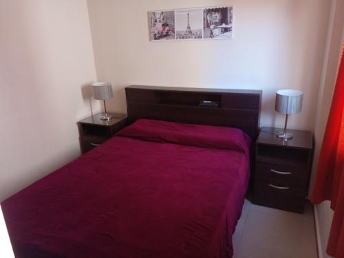 ein Schlafzimmer mit einem roten Bett mit zwei Nachttischen in der Unterkunft Departamento en Carlos Paz para familias in Villa Carlos Paz