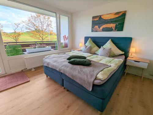 - une chambre avec un lit bleu et une grande fenêtre dans l'établissement Ferienwohnung BergOase, à Scheidegg