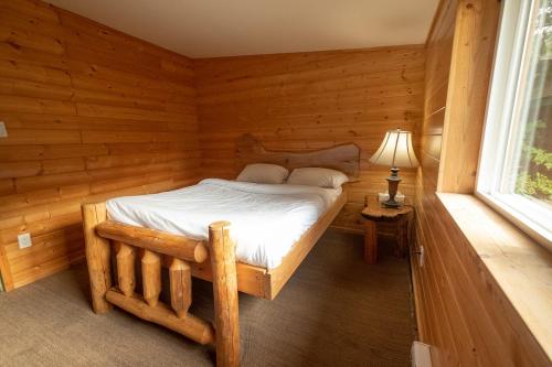 1 dormitorio con 1 cama en una cabaña de madera en Wild Coast Wilderness Resort, en Port Renfrew