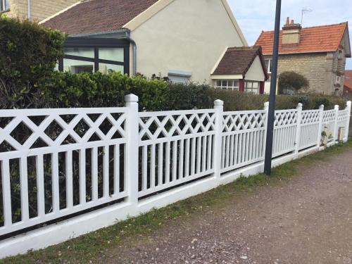 una cerca blanca frente a una casa en Luc sur mer, en Luc-sur-Mer
