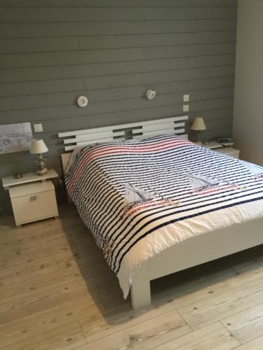 1 dormitorio con 1 cama grande y edredón a rayas en Luc sur mer, en Luc-sur-Mer