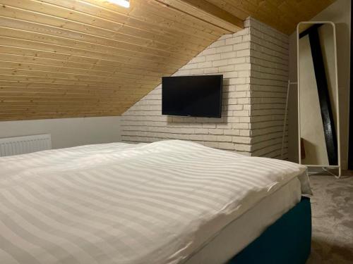 a bedroom with a bed and a tv on a brick wall at Tiny Dream House in Buşteni