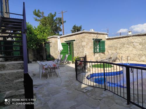 un patio con mesa y sillas y un edificio en Andrianna's Cottage, en Pano Akourdalia