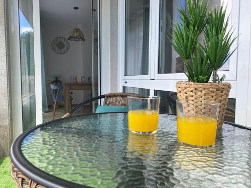 dos vasos de zumo de naranja sentados en una mesa de cristal en Samil primera línea de playa, en Vigo