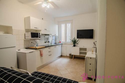 a kitchen with white cabinets and a tv in a room at Borgo Cocconi 33 in Parma