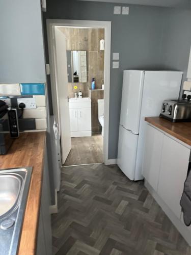 a kitchen with a white refrigerator and a sink at Wymington House in Bedford