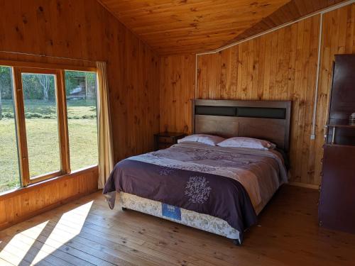 a bedroom with a bed in a wooden cabin at Cabaña Coigües alberto vanz con vista al mar in Quellón